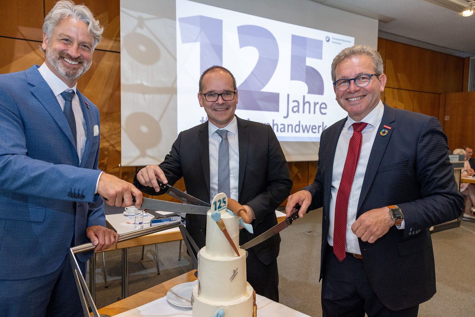 Peter Karst, Wirtschaftsminster Grant Hendrik Tonne und Kammerpräsident Thomas Gehre (v.l.n.r.) machen den Tortenanschnitt.
