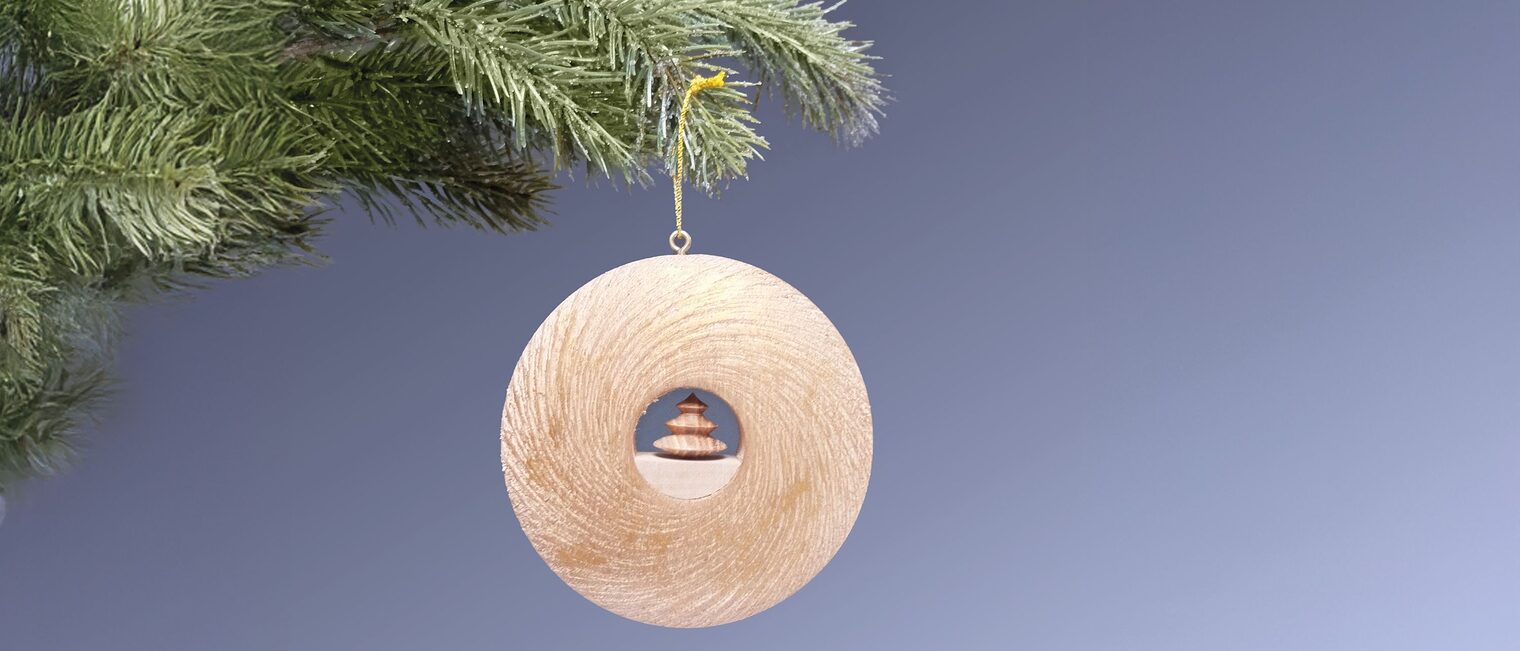 Runder Holzanhänger-Ring mit kleinem Weihnachtsbaum in der Mitte hängt an Tannenzweig.