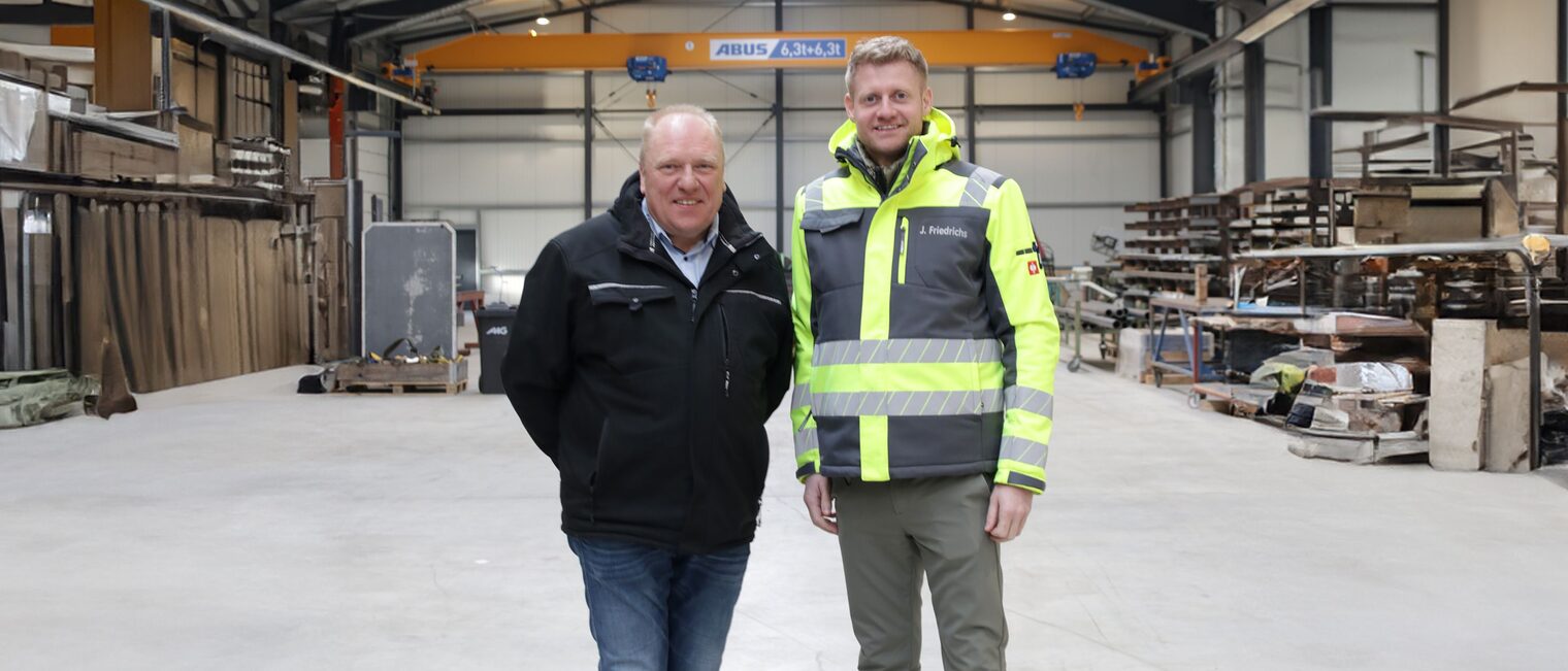 Jannes Friedrichs (re.) und Holger Bremer (li.) in der Halle Ihres Betriebs nebeneinander stehend.