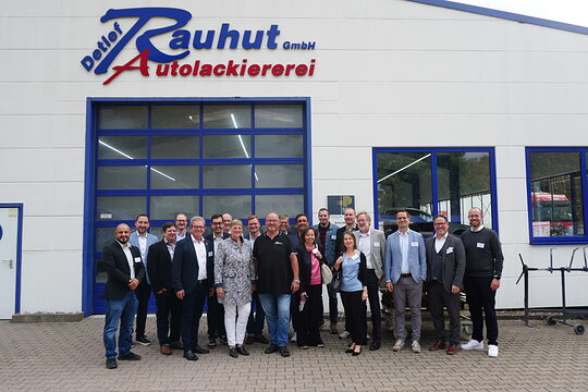 Gruppe steht vor einem großen Hallenstor der Autolackierer Rauhut.