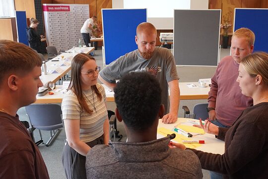 Gruppe von Gesellen beim Workshop am Tisch bei Gruppenaufgabe.